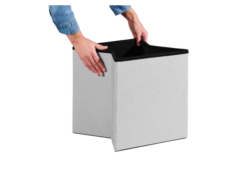 Mains ouvrant une boîte de rangement en tissu gris clair avec intérieur noir.