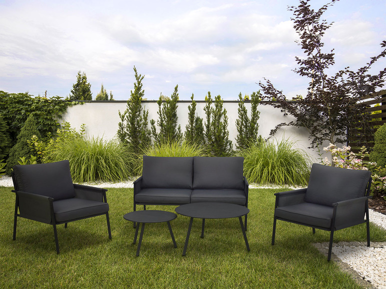 Een zwarte loungeset met twee fauteuils, een bank en twee tafels in een tuin.