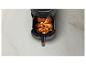 Airfryer met knapperige kippenpoten op een licht aanrecht.