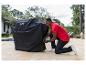 Un homme met une housse de protection Char-Broil sur un barbecue.