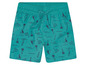 Short de bain turquoise avec un imprimé de palmiers, de bateaux et de planches de surf.