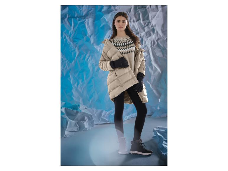 Vrouw in beige jas, patroon trui, zwarte legging en winterlaarzen