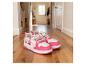 Chaussures pour enfants roses et blanches avec personnages de dessins animés sur un sol en bois.