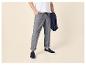 Homme en t-shirt blanc, pantalon gris et mocassins bleus, tenant une veste bleue.