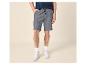 Homme en t-shirt bleu et short gris à cordon, baskets blanches.