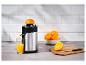 Presse-agrumes en acier inoxydable avec jus d'orange fraîchement pressé et fruits.