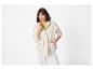 Vrouw in een lichtbeige utility jack, limoengroene top en witte wide-leg broek.