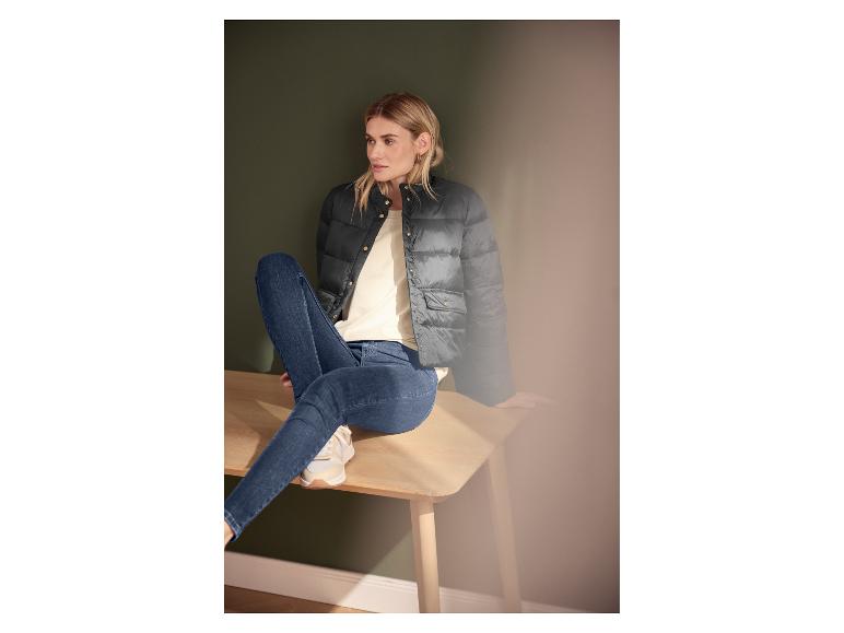 Femme en doudoune noire et jean assise sur un banc en bois.