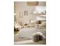 Slaapkamer in neutrale tinten met bed, vloerkleed, fauteuil en wanddecoraties.