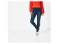 Une femme portant un jean skinny bleu foncé et des baskets blanches.