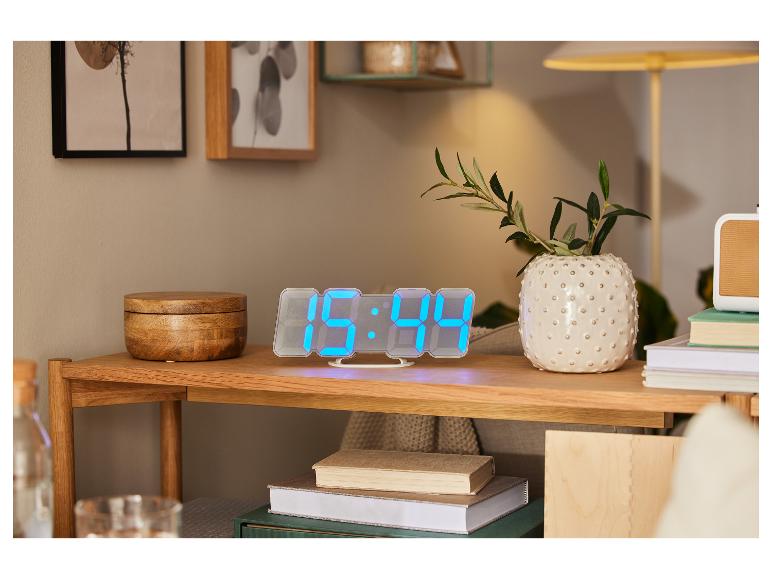 Digitaal LED-klokje, boeken en decoratieve vaas op houten meubel.