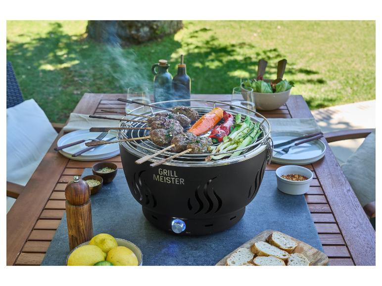 Barbecue avec brochettes de viande et légumes sur une table extérieure, entouré de vaisselle et d'épices.