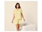 Femme souriante en pyjama jaune à manches courtes et short, avec liseré blanc.