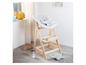 Une chaise haute en bois Stokke Tripp Trapp avec un coussin gris et des jouets.