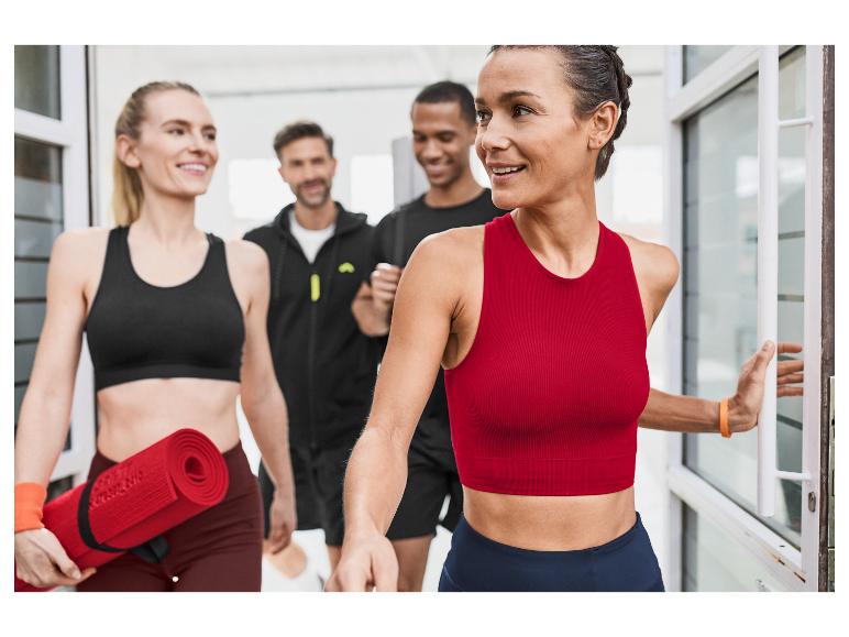 Des femmes en vêtements de sport Reebok entrent dans un studio de fitness, portant des tapis de yoga.