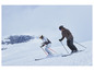 Deux skieurs en tenue de ski descendent une pente enneigée.