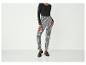 Une femme porte un haut noir et un pantalon à carreaux.