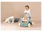 Lachende baby speelt met een Little Smoby poppenwagen met een pop erin.