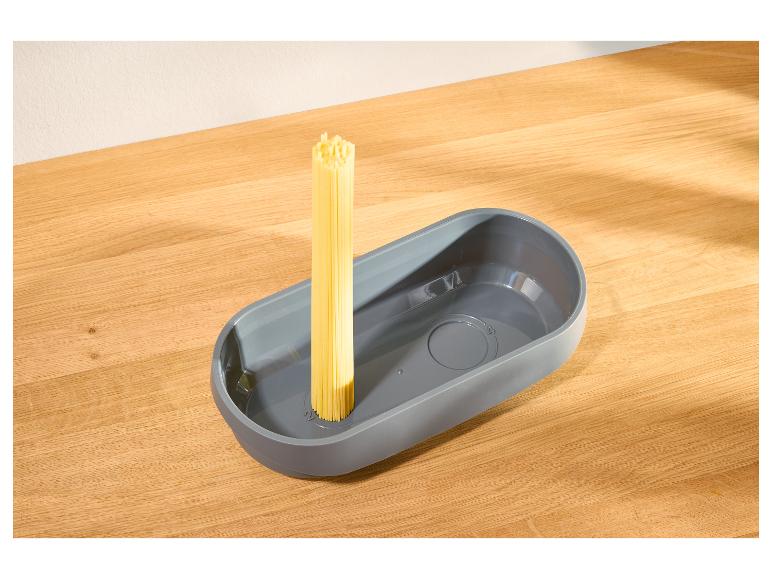 Grijze pastameter met rauwe spaghetti op een houten tafel.