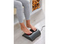 Une femme utilise un tapis de massage électrique pour les pieds avec fonction de chaleur.