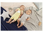 Twee baby's in rompers op een gebreid kleed.