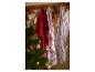 Kerstthema keukendoeken en decoraties hangend aan een houten rek naast een kerstboom.
