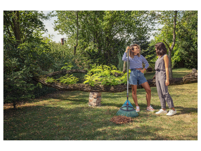 Deux femmes dans un jardin avec un râteau et des feuilles.