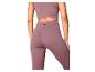 Femme portant un ensemble d'entraînement mauve, avec un crop top et un legging taille haute.