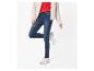 Femme en veste beige, pull rouge et jean skinny bleu avec des baskets beiges.