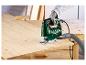 Groene Parkside decoupeerzaag zaagt een houten plank op een werkbank.