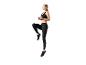 Femme en brassière de sport noire et leggings faisant de l'exercice.