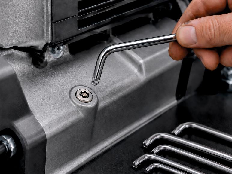 Main utilisant une clé Torx pour serrer une vis sur une pièce métallique.