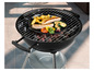 Een zwarte ronde barbecue met grillrooster en een rooster met worstjes, aardappelen en courgette.