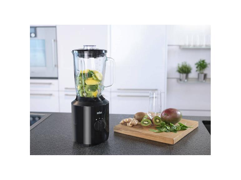 Blender met fruit en groenten in een keuken