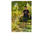 Man in zwart T-shirt en groene korte broek besproeit bloemen in een tuin.