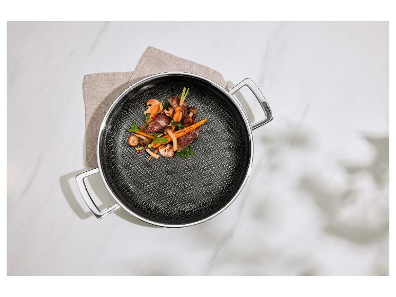 Koekenpan met vlees, champignons en wortels op een theedoek op een marmeren tafel