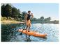 Homme faisant du paddleboard sur un lac entouré d'arbres et de montagnes.