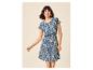 Femme souriante dans une robe bleue à motifs avec des manches courtes et une taille élastique.