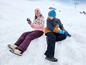 Twee kinderen in winterkleding spelen in de sneeuw.