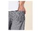 Homme en t-shirt blanc et short gris, la main dans la poche.