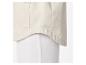 Detail van de onderzoom van een beige overhemd met zak, over een witte broek.