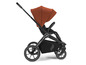 Een zwarte kinderwagen met een oranje kap en het merk 'Vamos'.