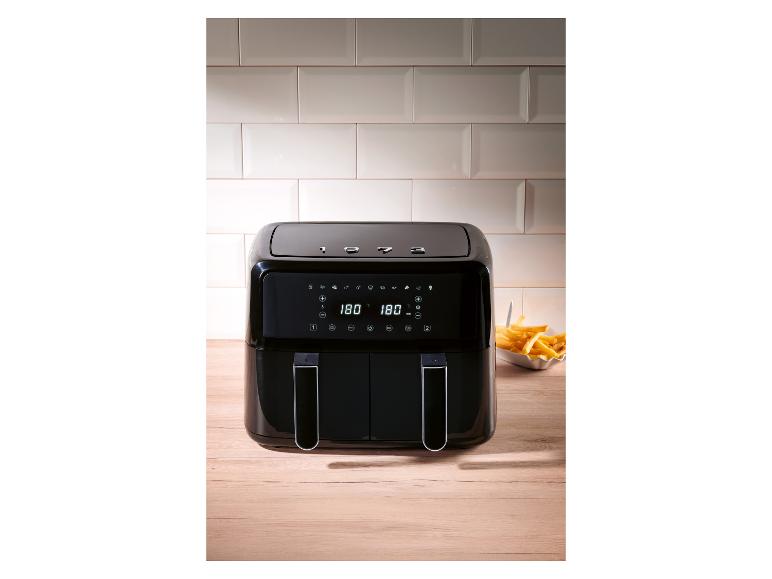 Een moderne, zwarte airfryer op een houten aanrecht.