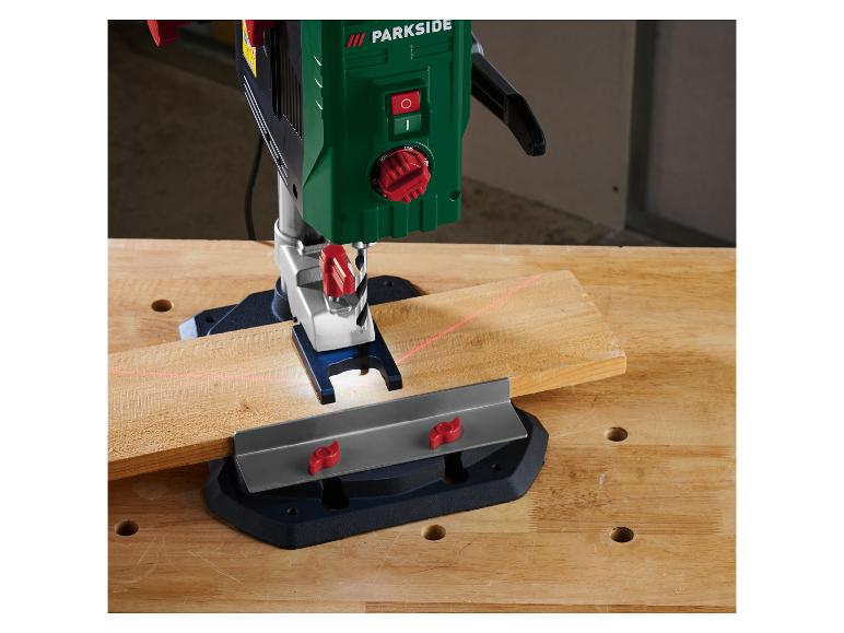 Support de perceuse avec laser et pièce de bois sur un établi.