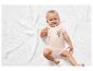 Baby op een witte deken met een roze romper met koala print.