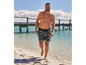 Homme en short de bain à imprimé palmier sur la plage.