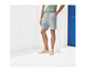 Man draagt gestreepte korte broek en witte sneakers.