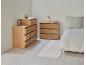 Deux commodes en bois et un lit avec des draps blancs dans une pièce claire.