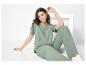 Femme en t-shirt et pantalon verts assise par terre avec une décoration blanche.