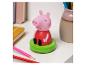 Figurine de cochon rose sur base verte, avec des crayons colorés et des cahiers.